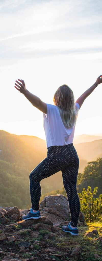 Une femme de dos en pleine nature qui célèbre le lever de soleil illustrant les prises en charge de naturopathie et réflexologie de l'anxiété