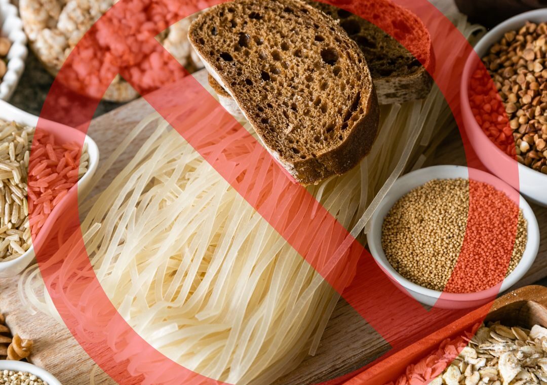 Table remplie d'aliments riches en gluten avec un panneau "stop" pour illustrer un atelier naturopathique sur l'évictiondu gluten